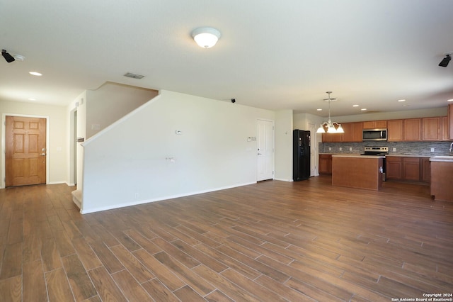 kitchen featuring stainless steel appliances, dark hardwood / wood-style floors, backsplash, a chandelier, and decorative light fixtures