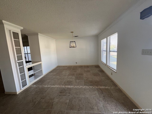 spare room with crown molding and a textured ceiling