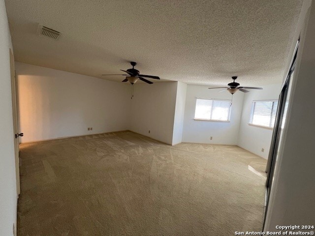 carpeted spare room with a textured ceiling and ceiling fan