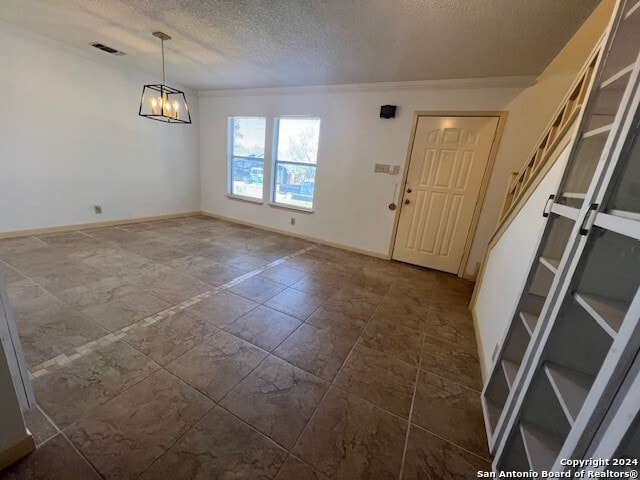 foyer with a chandelier, a textured ceiling, and ornamental molding