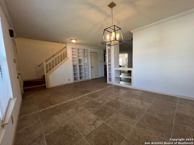 unfurnished dining area with a textured ceiling, a notable chandelier, and crown molding