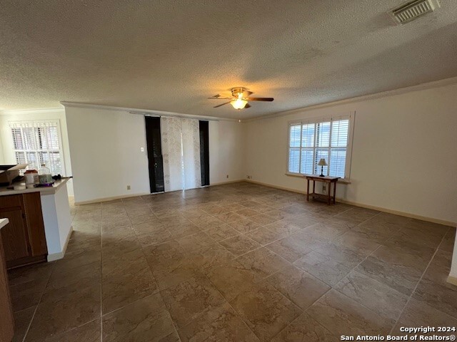 spare room with ceiling fan, ornamental molding, and a textured ceiling