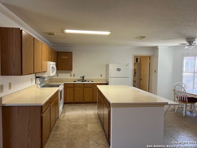 kitchen featuring a textured ceiling, white appliances, and sink