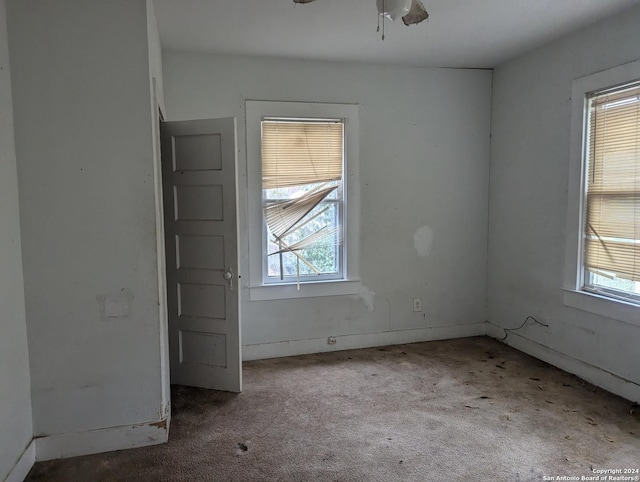 carpeted empty room featuring a wealth of natural light and ceiling fan