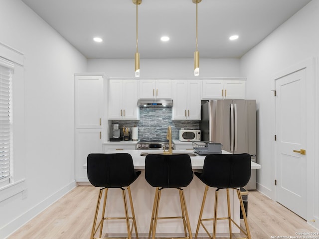 kitchen featuring decorative light fixtures, light hardwood / wood-style floors, white cabinetry, and stainless steel appliances