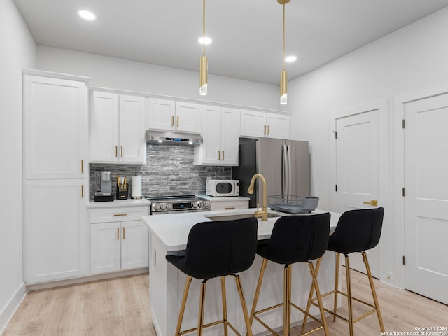 kitchen with white cabinetry, stainless steel appliances, decorative light fixtures, and light hardwood / wood-style floors