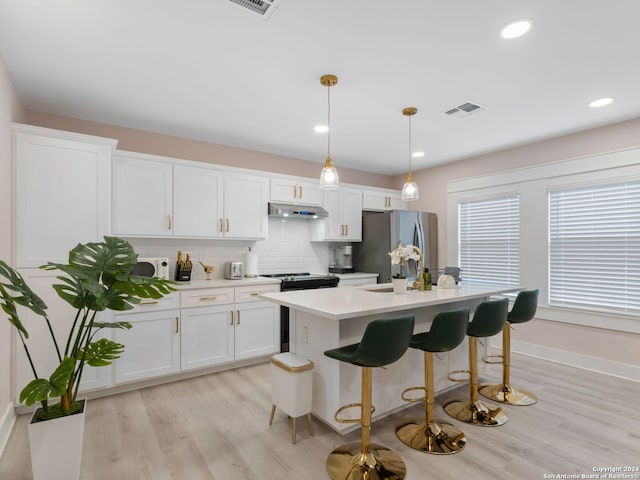 kitchen with white cabinets, pendant lighting, stainless steel appliances, and light hardwood / wood-style flooring