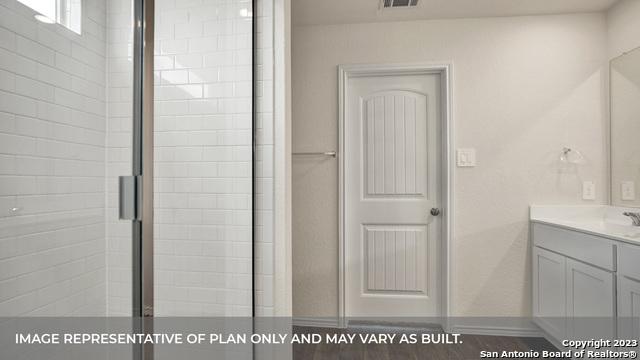 bathroom with hardwood / wood-style flooring, vanity, and a shower with shower door