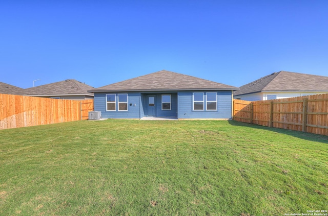 rear view of property with cooling unit and a yard