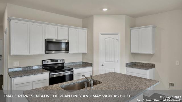 kitchen with white cabinets, stainless steel appliances, a kitchen island with sink, and sink