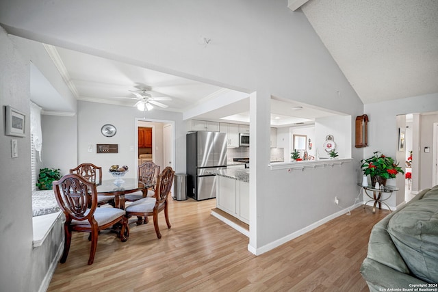 dining space with light wood-type flooring, high vaulted ceiling, ceiling fan, and crown molding