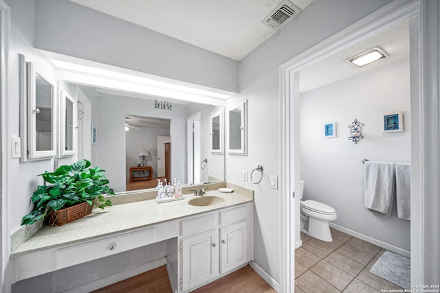 bathroom with toilet, a textured ceiling, vanity, and tile patterned floors