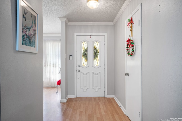 entryway with a textured ceiling, light hardwood / wood-style floors, and crown molding