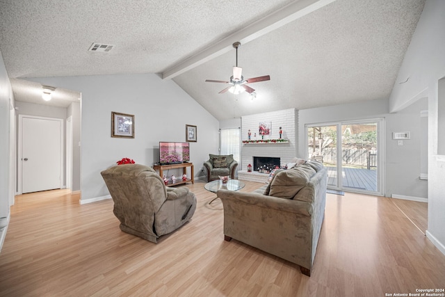 living room featuring beam ceiling, ceiling fan, a brick fireplace, light hardwood / wood-style flooring, and high vaulted ceiling