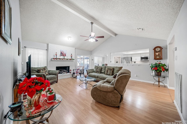 living room with high vaulted ceiling, a brick fireplace, ceiling fan, beamed ceiling, and light hardwood / wood-style floors