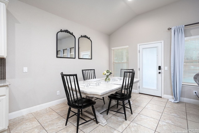 tiled dining area featuring vaulted ceiling