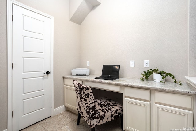 home office with built in desk and light tile patterned floors