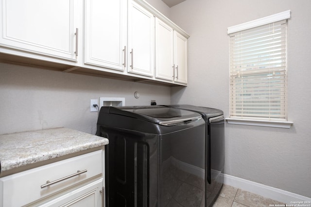 laundry room with cabinets, light tile patterned floors, and washer and dryer