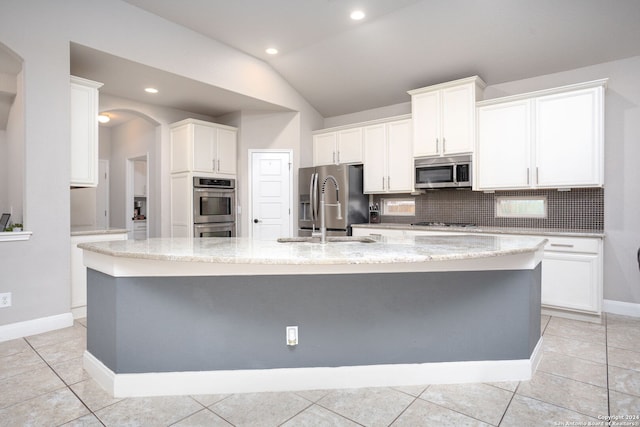 kitchen featuring stainless steel appliances, lofted ceiling, and an island with sink