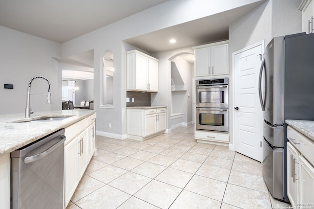 kitchen with light stone countertops, sink, white cabinets, and appliances with stainless steel finishes