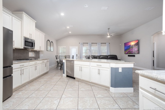 kitchen with light tile patterned flooring, an island with sink, lofted ceiling, white cabinets, and appliances with stainless steel finishes