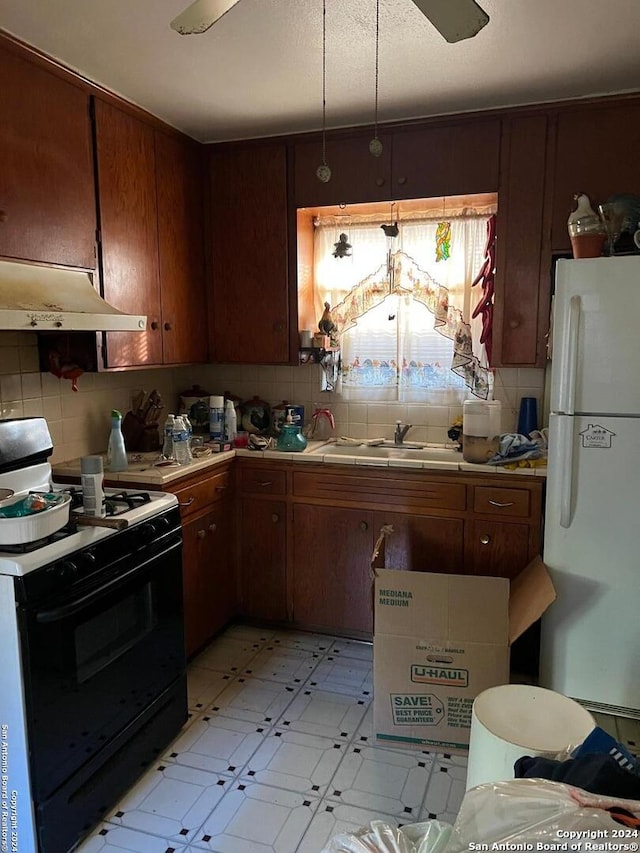 kitchen with decorative backsplash, white appliances, sink, and range hood