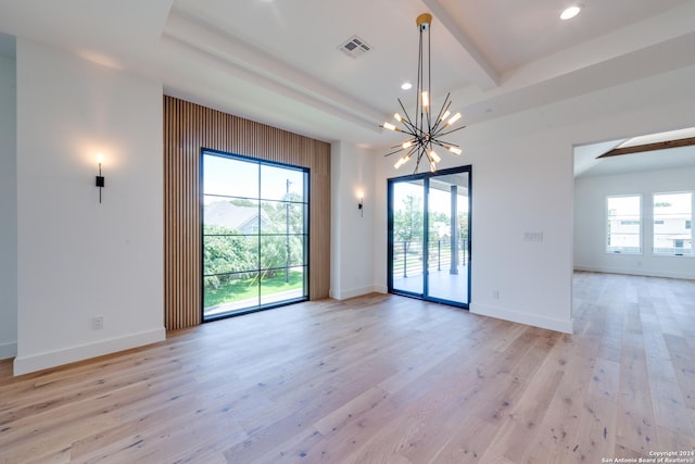 empty room with beamed ceiling, plenty of natural light, a chandelier, and light hardwood / wood-style flooring