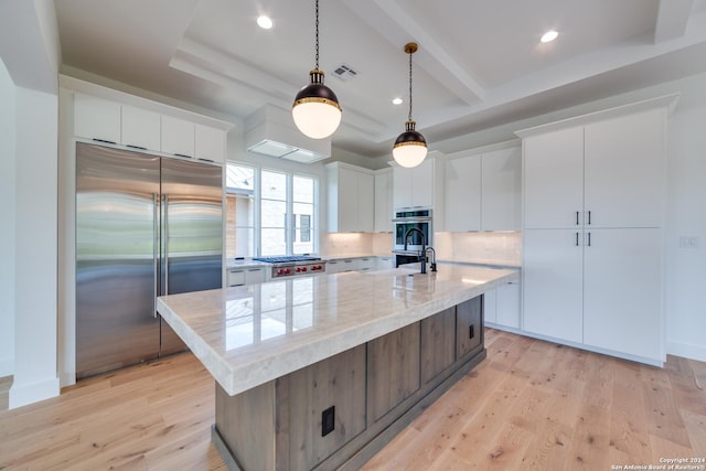 kitchen featuring a center island with sink, white cabinets, stainless steel appliances, and light hardwood / wood-style floors