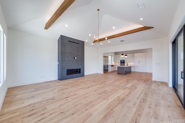 unfurnished living room with lofted ceiling with beams, light hardwood / wood-style floors, and a fireplace