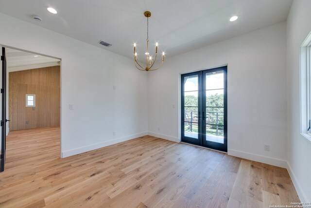 spare room featuring a chandelier, french doors, and light hardwood / wood-style floors