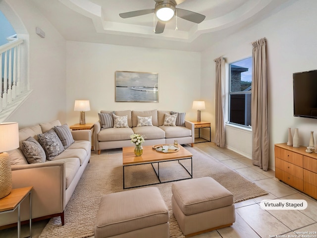 tiled living room featuring ceiling fan and a tray ceiling