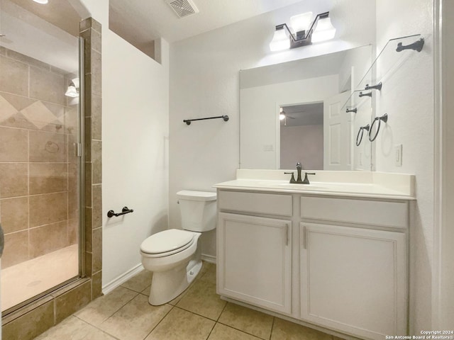 bathroom featuring tile patterned flooring, vanity, toilet, and a shower with shower door