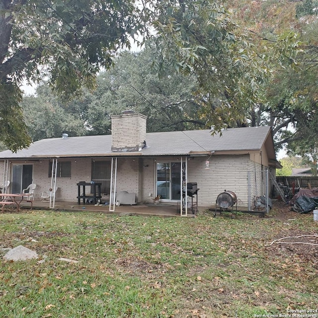 back of property with a lawn and a patio