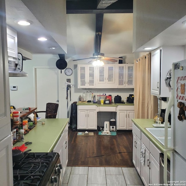 kitchen with black gas stove, white cabinets, wood-type flooring, and sink