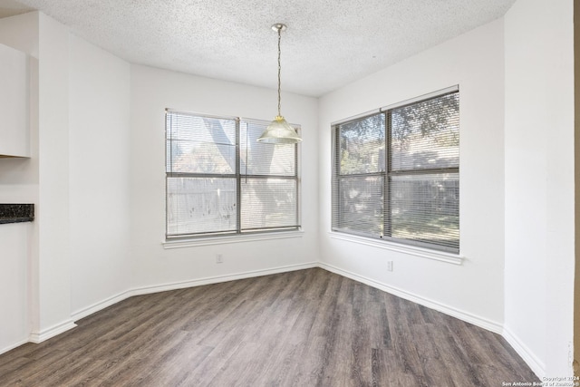 unfurnished dining area with a textured ceiling and dark hardwood / wood-style flooring