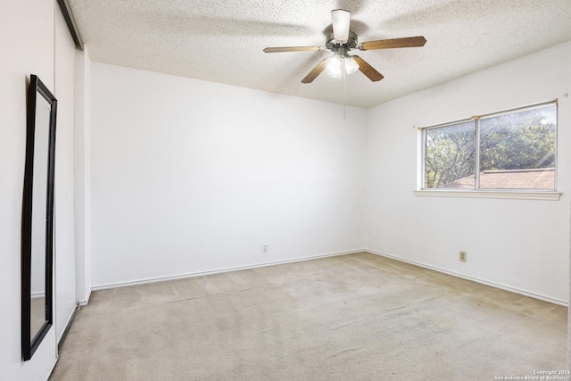 empty room with ceiling fan, a textured ceiling, and light carpet