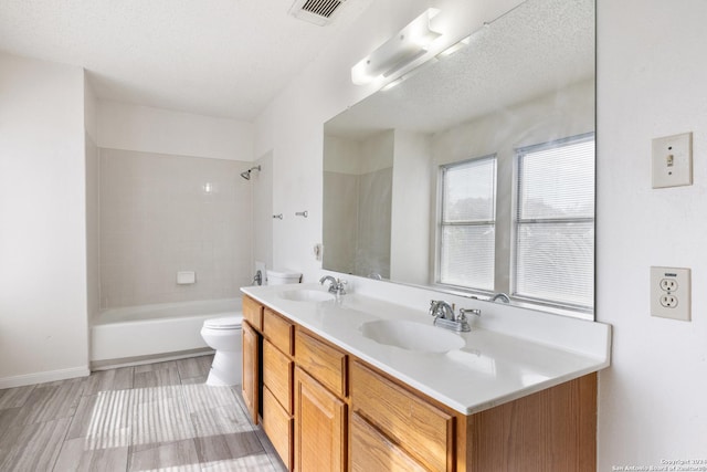 full bathroom featuring hardwood / wood-style floors, vanity, tiled shower / bath combo, toilet, and a textured ceiling