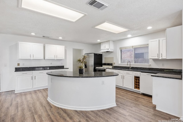 kitchen featuring white cabinetry, sink, a center island, white appliances, and light wood-type flooring