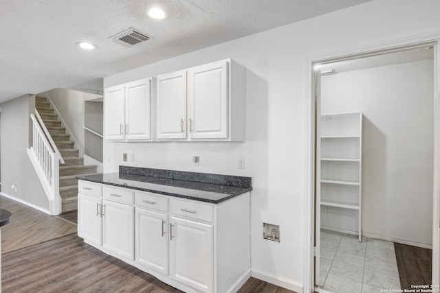 kitchen featuring white cabinetry, a textured ceiling, and hardwood / wood-style flooring