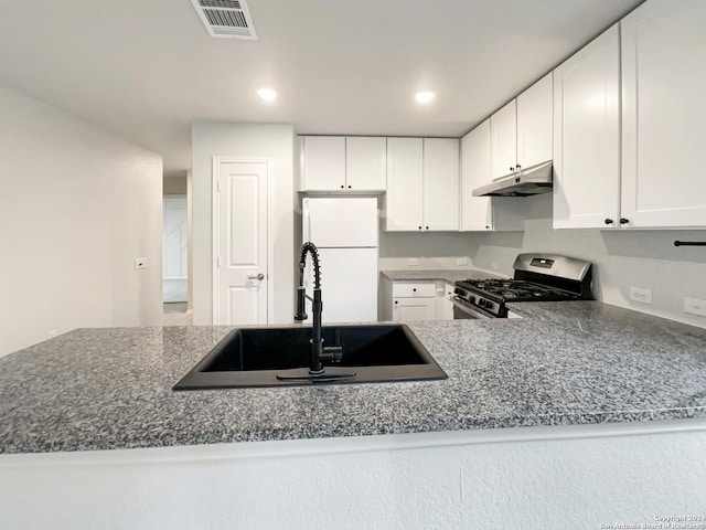 kitchen featuring white cabinets, white refrigerator, sink, stone countertops, and stainless steel range with gas stovetop