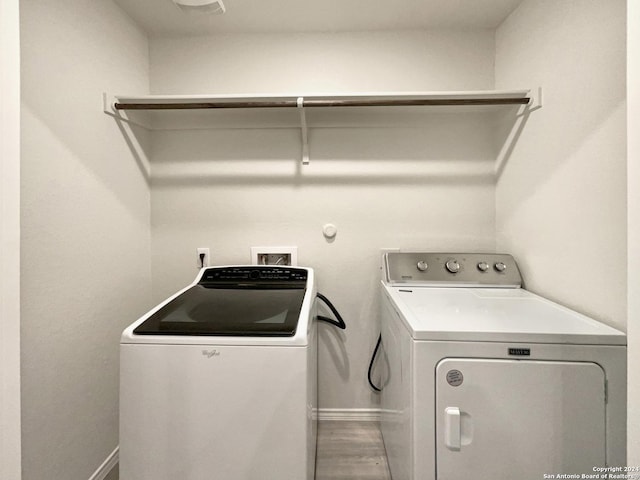 clothes washing area with hardwood / wood-style floors and washing machine and dryer