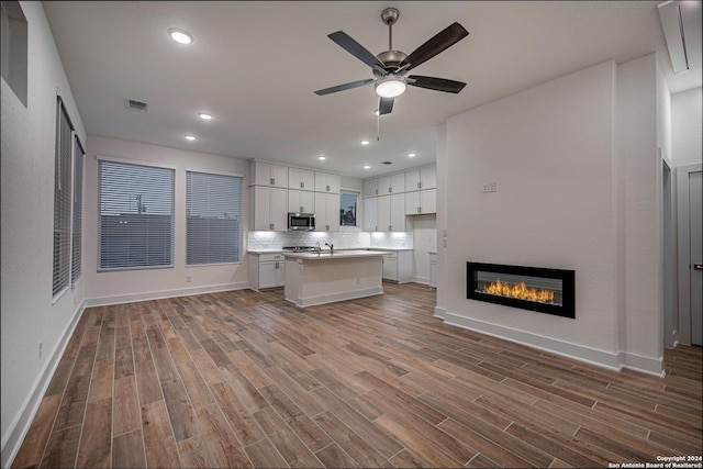 kitchen featuring a center island, white cabinets, ceiling fan, decorative backsplash, and light hardwood / wood-style floors