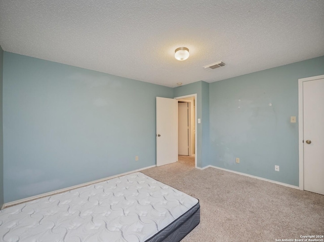 unfurnished bedroom with a textured ceiling and light colored carpet