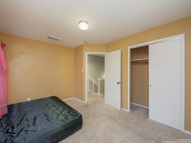 unfurnished bedroom featuring a textured ceiling, light colored carpet, and a closet