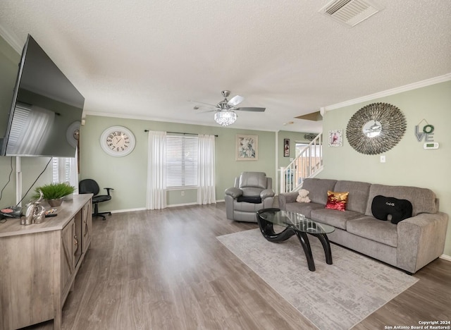 living room featuring a textured ceiling, wood-type flooring, and ornamental molding