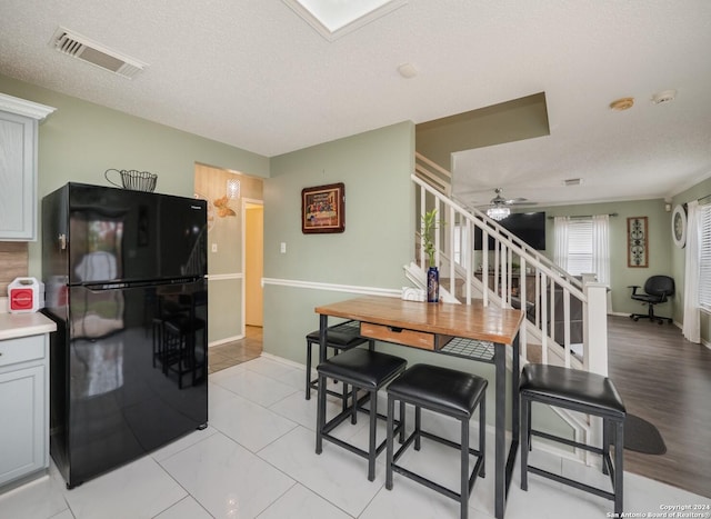 dining area with a textured ceiling, light hardwood / wood-style flooring, ceiling fan, and ornamental molding