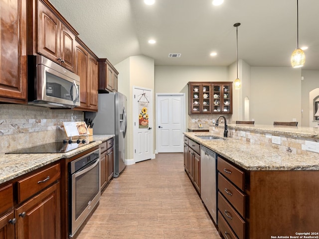 kitchen with pendant lighting, sink, decorative backsplash, light hardwood / wood-style floors, and stainless steel appliances