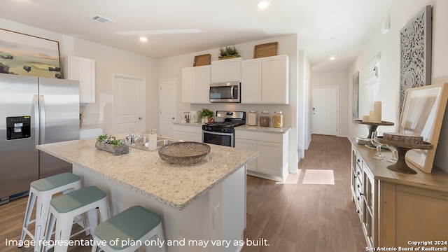 kitchen with sink, light wood-type flooring, an island with sink, white cabinetry, and stainless steel appliances