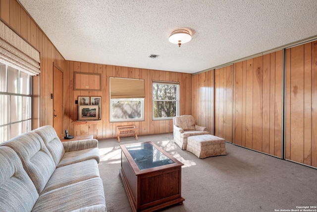 carpeted living room with wooden walls and a textured ceiling