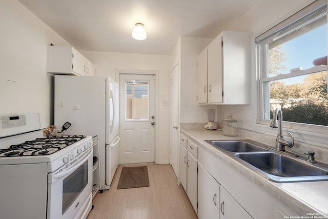 kitchen with white range with gas cooktop, white cabinetry, and sink